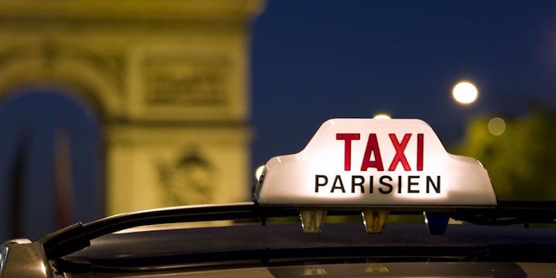 Enseigne de taxi parisien la nuit avec l'Arc de Triomphe